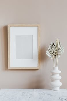 Elegant minimalist interior with a wooden frame and sculptural vase on a marble surface.