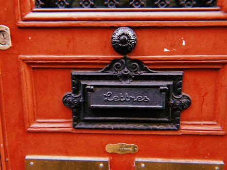 Classic French letterbox on a red wooden door in Paris.