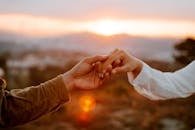 pexels photo 5108999 5108999 A couple shares a tender moment, holding hands during a beautiful sunset in the countryside.