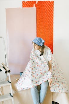 A young woman sitting in a room with colorful wallpapers, preparing for home renovation.