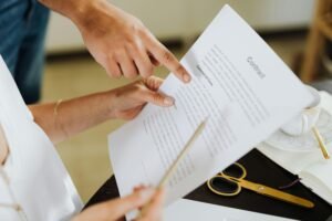 pexels photo 4968563 4968563 Close-up of two people discussing a business contract at a desk in an office setting.
